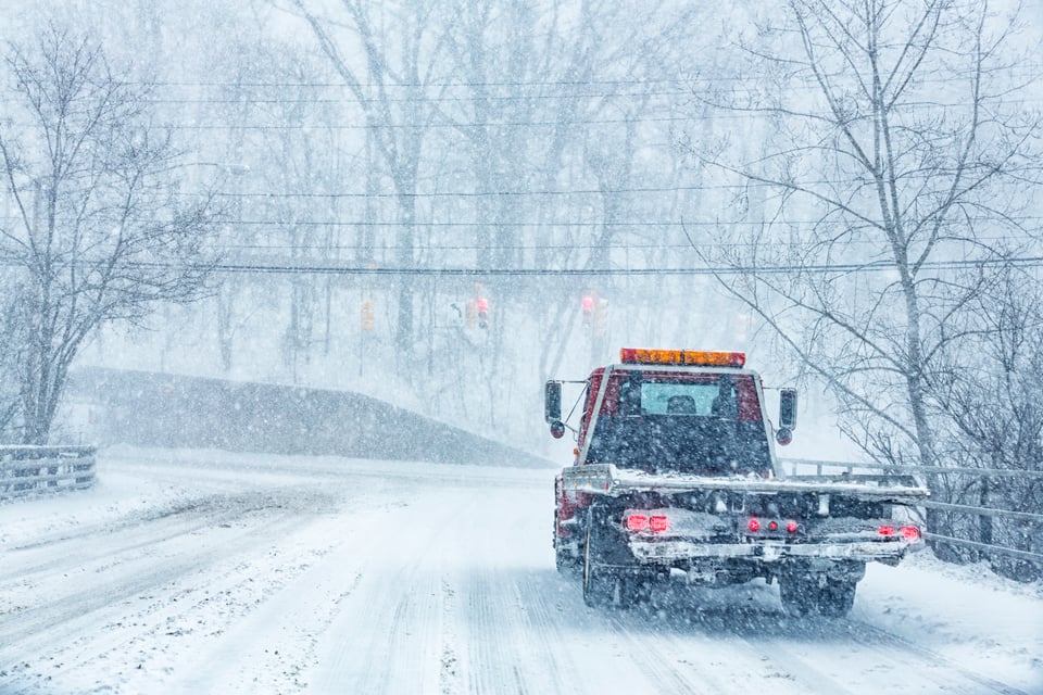 Tow truck driving in a snow storm.