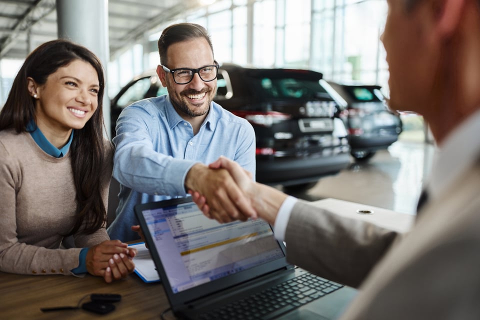 Happy couple came to an agreement with car salesperson in a showroom [1426471634]